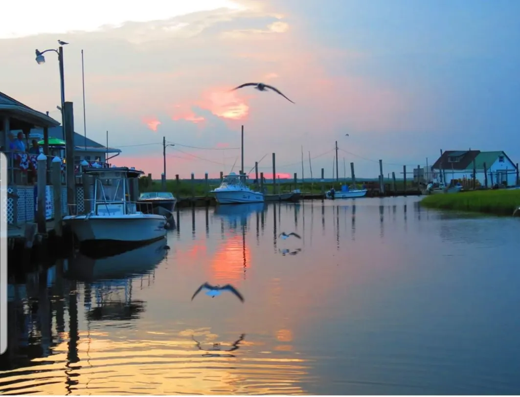Boats moored on Oyster Creek beneath the evening sky
